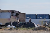 A police officer stands in a salvage yard.