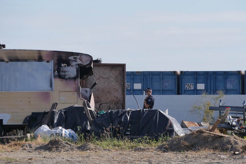 A police officer stands in a salvage yard.