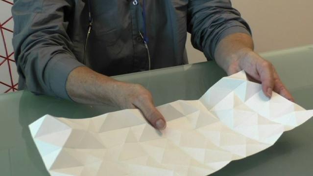Hands holding paper with folded creases in it
