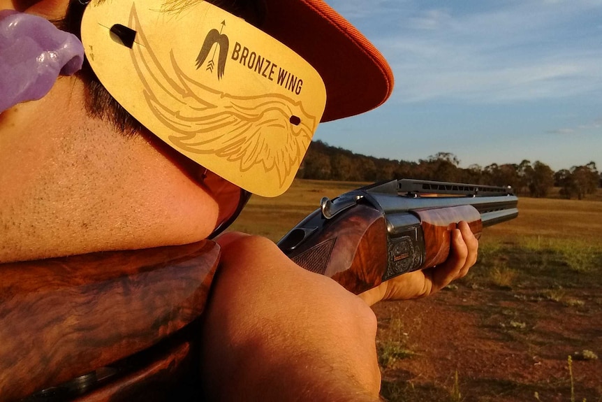 An unidentifiable man shoots a gun for clay-target shooting.