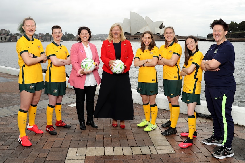 A group of women pose in green an gold uniforms