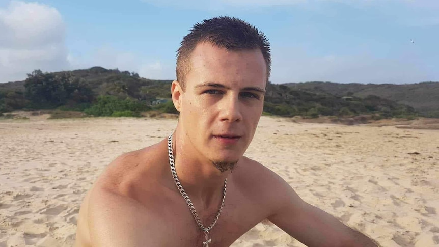 A young fair man wearing a chain on the beach