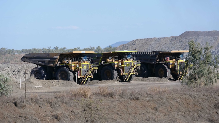 Three large coal mining trucks in a row