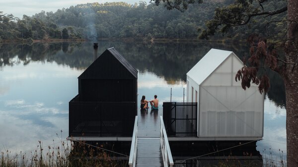 A sauna building and change tent on a floating pontoon on a peaceful lake.