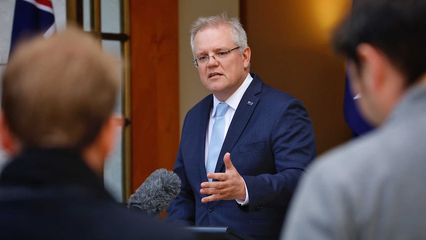 Scott Morrison flanked by journalists.