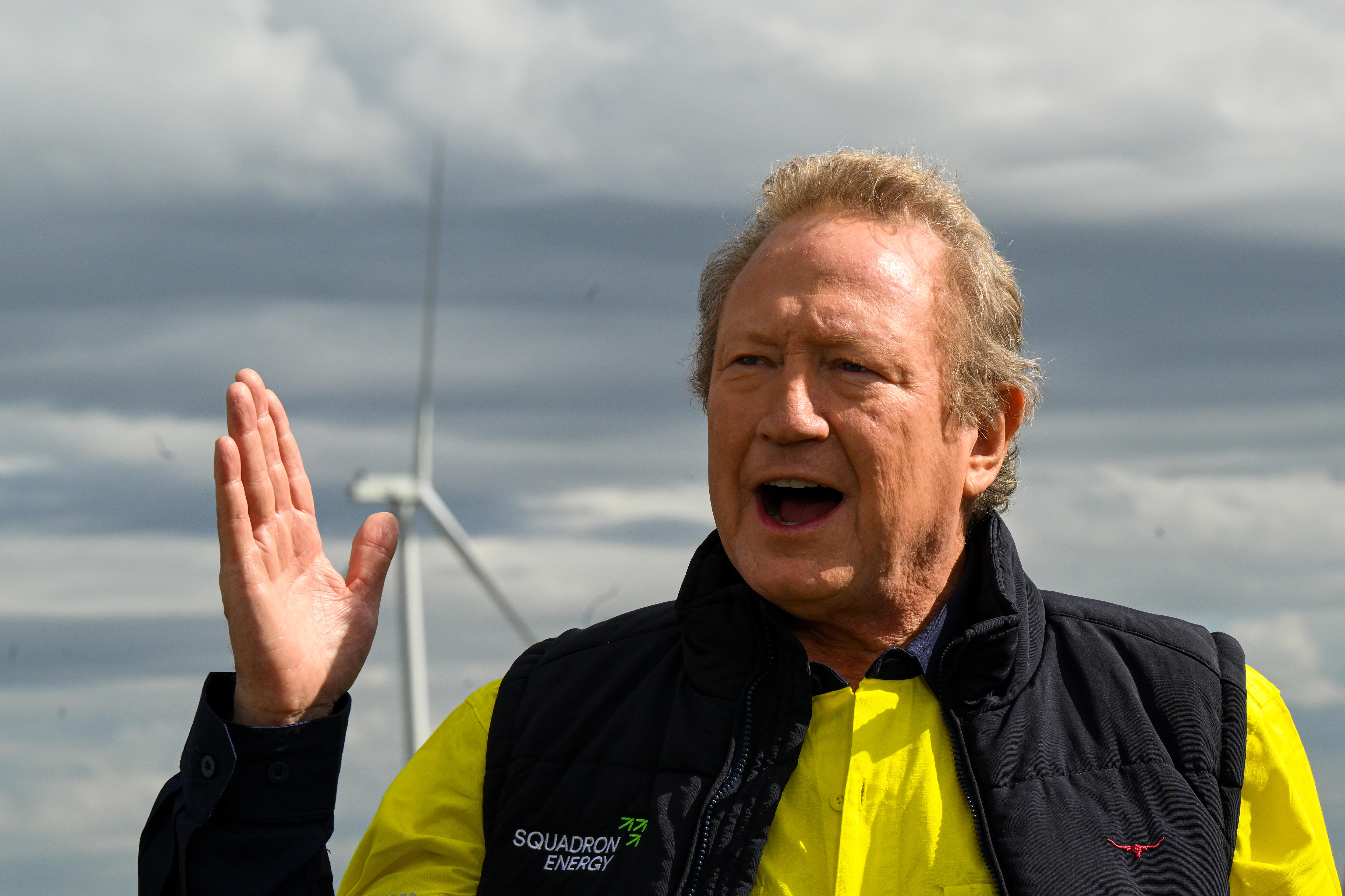 A close up of a middle-aged man in a high-viz polo shirt and padded vest, speaking outside and gesturing with one hand