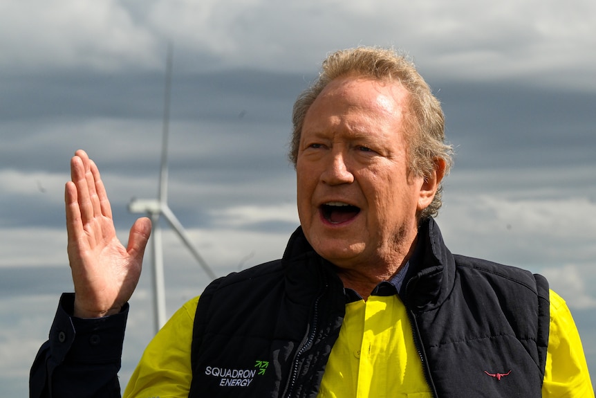 A close up of a middle-aged man in a high-viz polo shirt and padded vest, speaking outside and gesturing with one hand