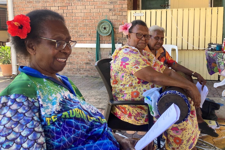 a group of women sit around singing