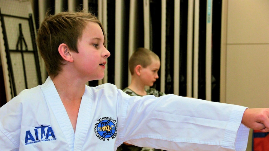 A boy puts his arm out inside a Taekwondo class. October, 2018.