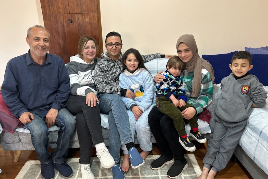 Rami's parents, his three children and wife sit on the couch of their home.
