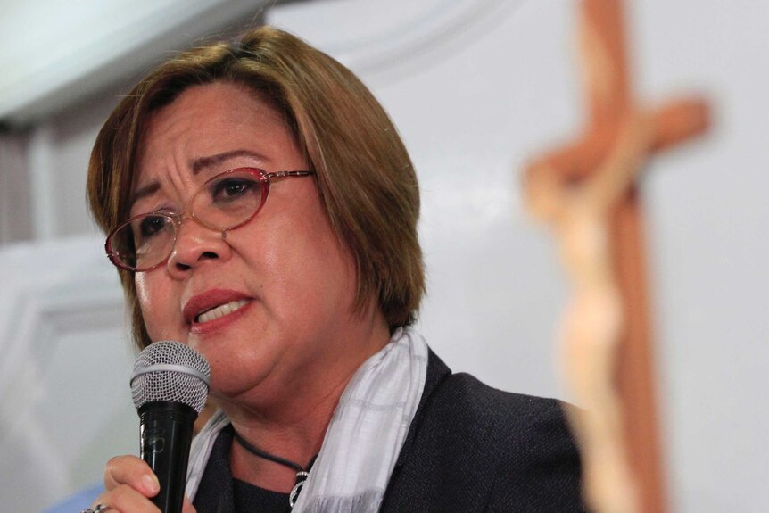 A close up of Philippine Senator Leila de Lima holding a microphone during a speech in a church.