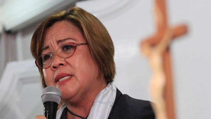 A close up of Philippine Senator Leila de Lima holding a microphone during a speech in a church.