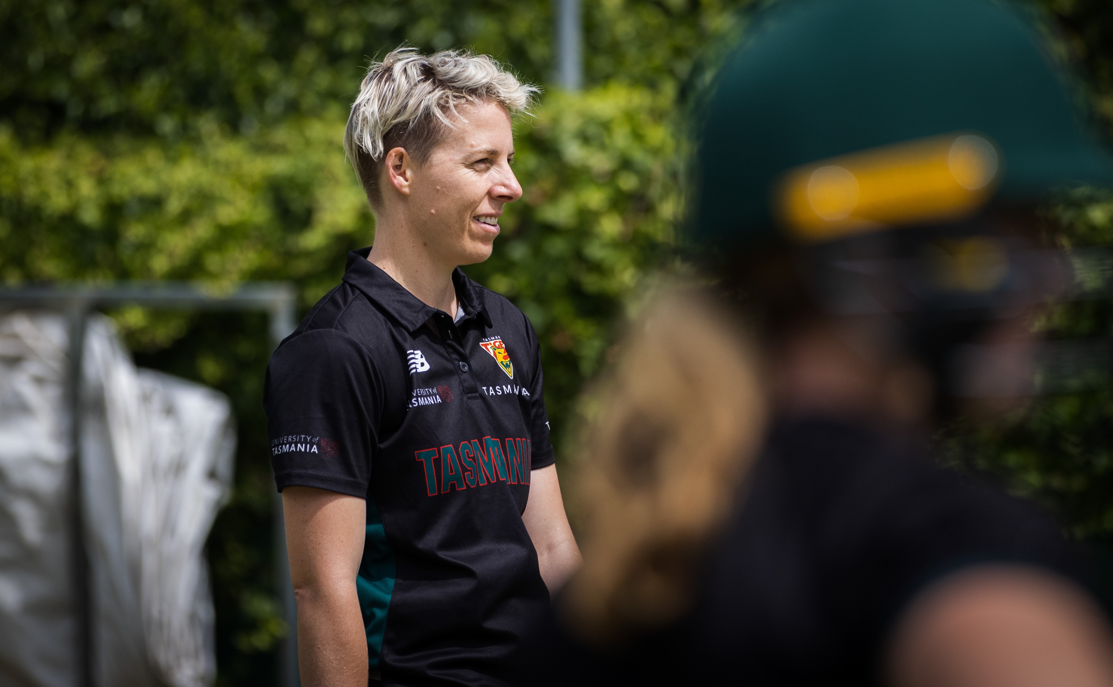 Una mujer rubia baja mira hacia el lado de la cámara.