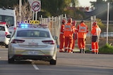 Five SES Rescue men wearing orange suits standing together at the scene of a crime