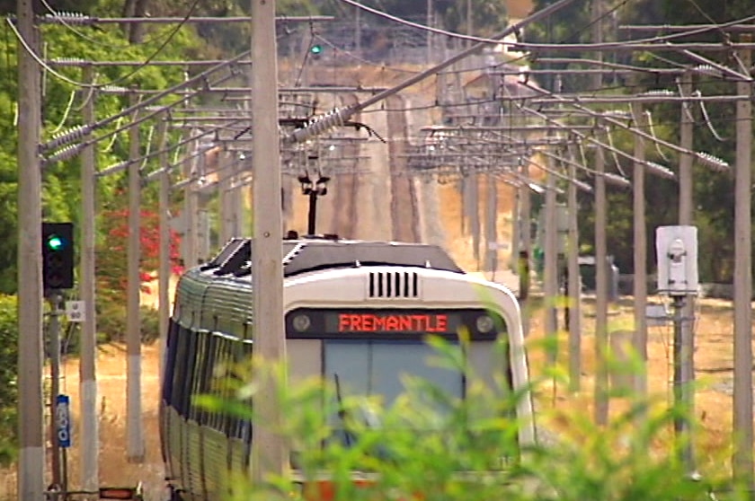 A train moves along a train line with cascading overhead wires