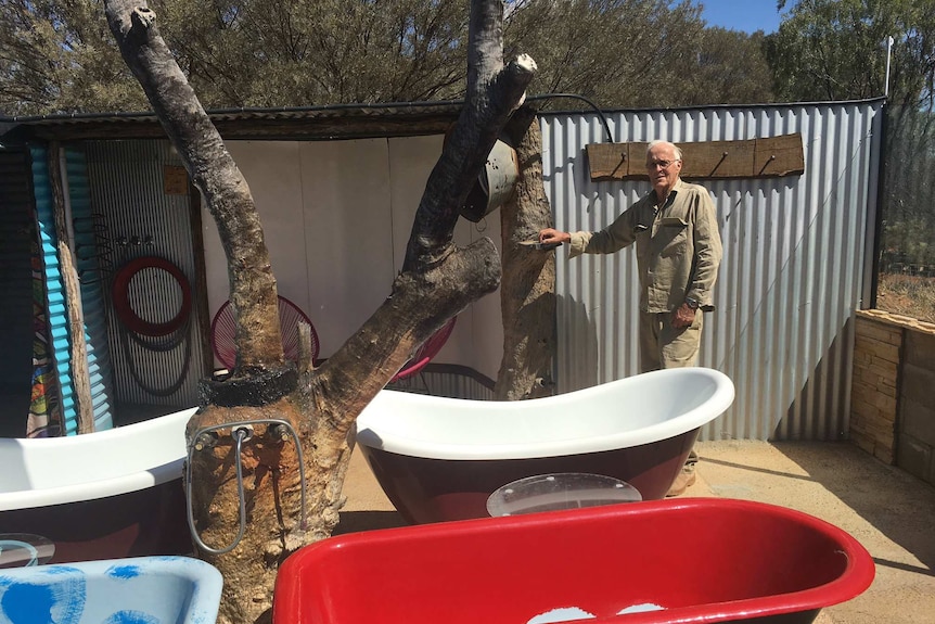 A man stands in front of four outdoor baths