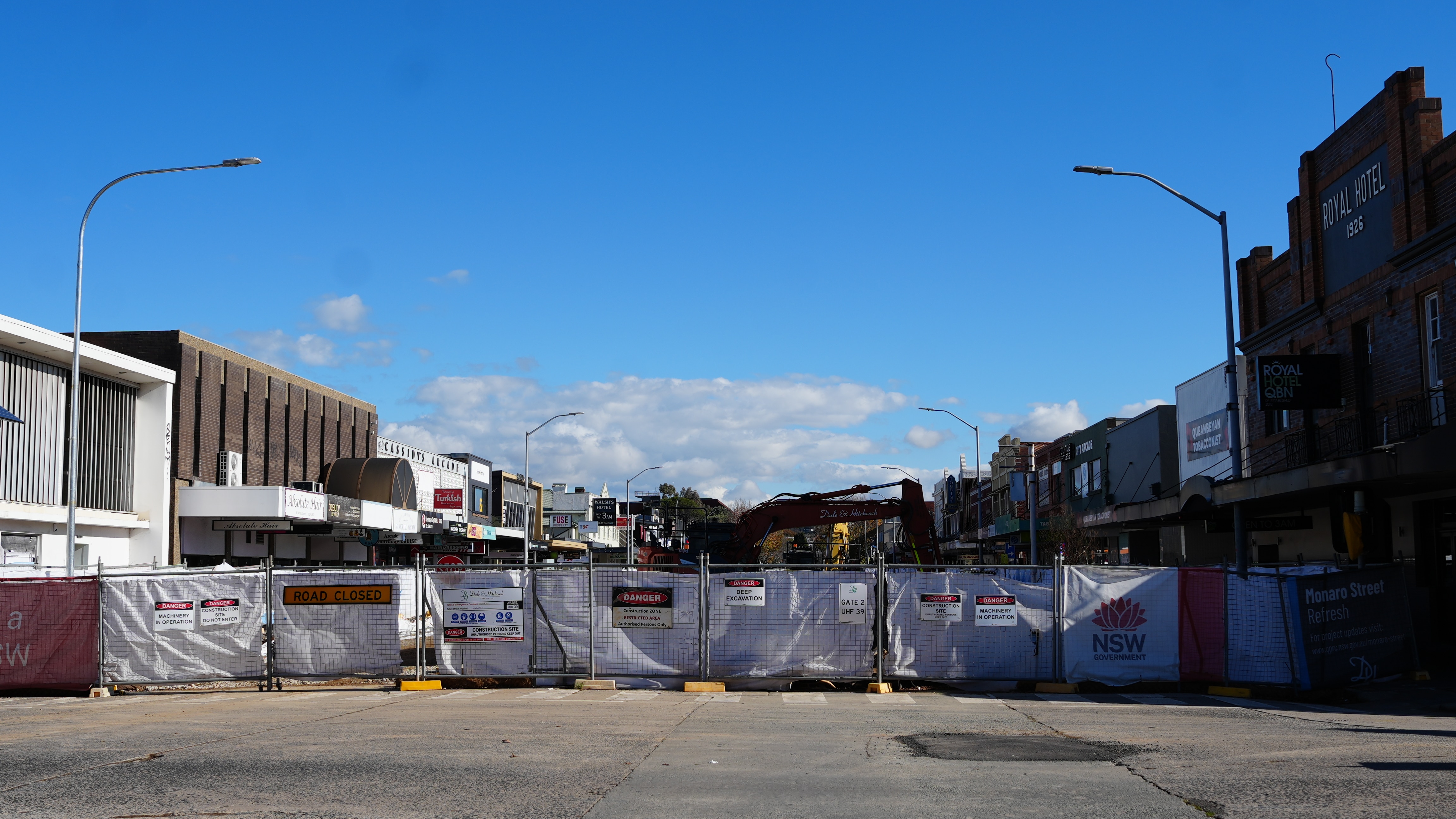 A street with buildings on either side, with a covered fence closing off the entrance.
