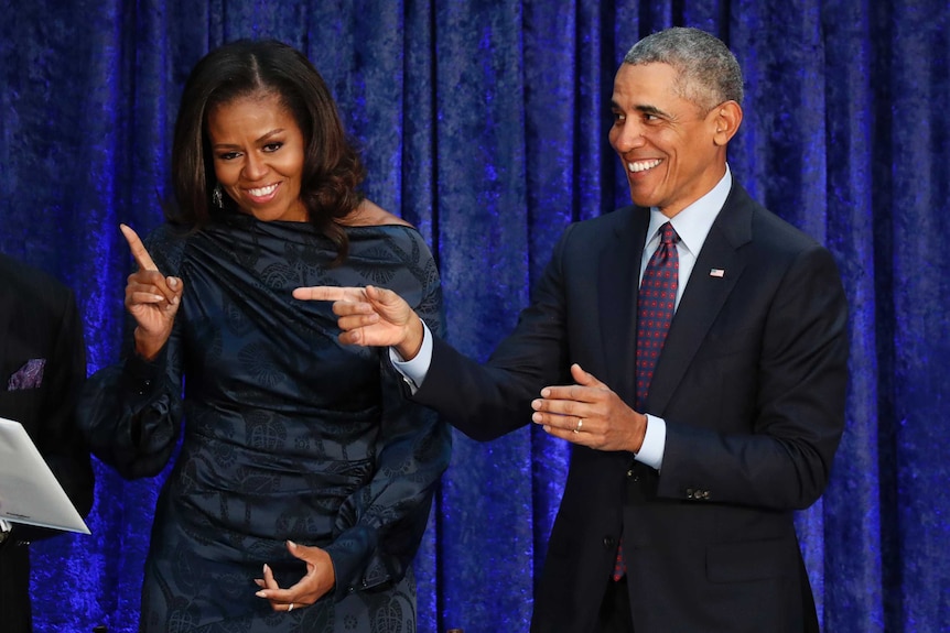 Former US President Barack Obama and former first lady Michelle Obama react to a crowd
