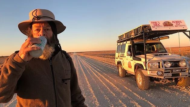 Phil McDonald has a drink on a long, dusty road at sunset.