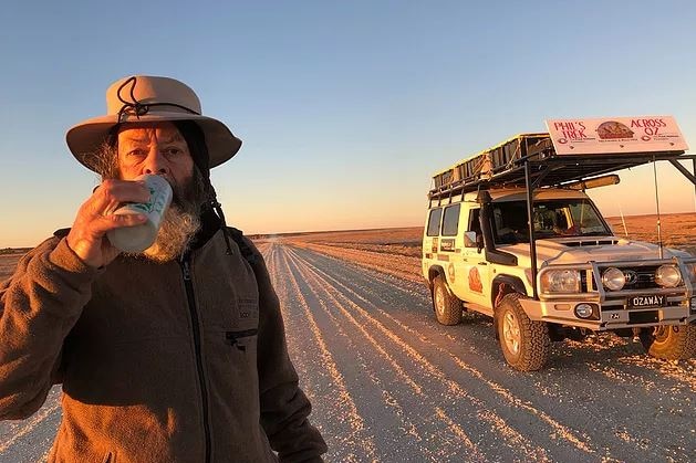 Phil McDonald has a drink on a long, dusty road at sunset.