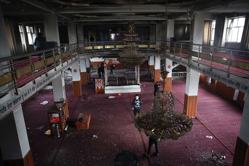 Afghan Journalists film inside a large high hall with a high ceiling in Sikh house of worship.