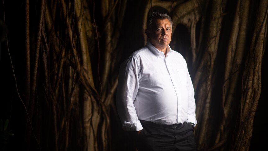 Indigenous barrister Tony McAvoy stands in front of a large tree.