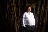 Indigenous barrister Tony McAvoy stands in front of a large tree.