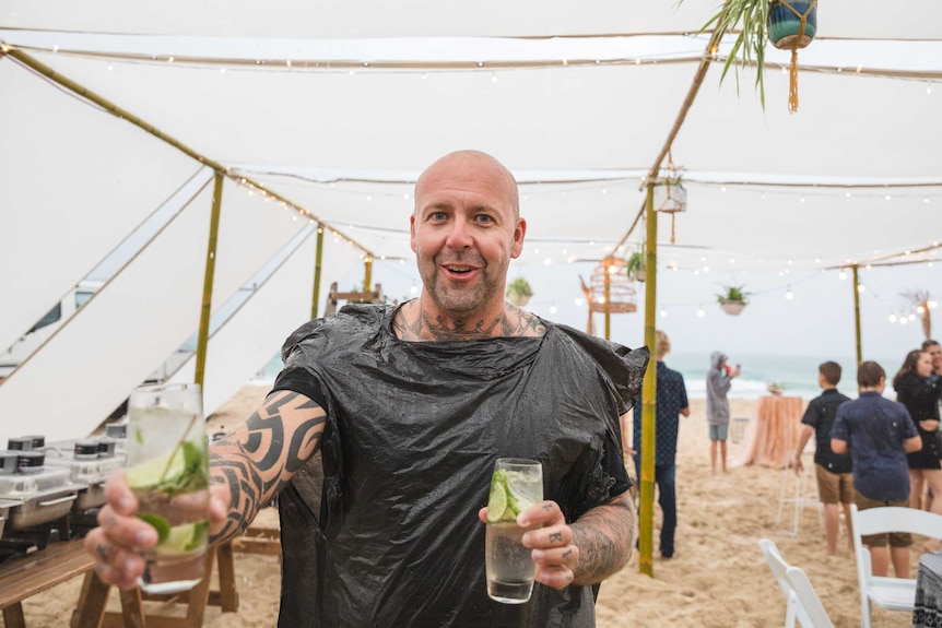 A party-goer wears a plastic bag for rain protection during a washed-out beach party on Stradbroke Island.