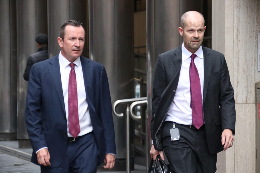 A wide shot of WA Premier Mark McGowan walking outside alongside another man.