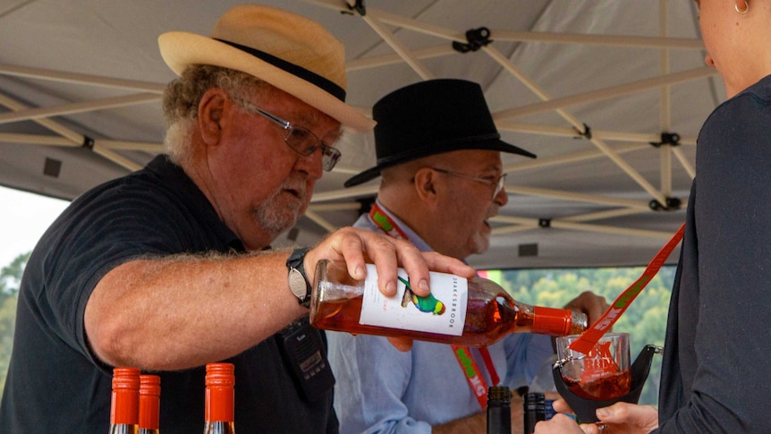 A man pours wine into a glass at what appears to be a festival