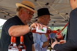 A man pours wine into a glass at what appears to be a festival