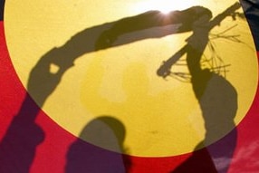 An Aboriginal elder silhouetted behind the Aboriginal flag. (Torsten Blackwood/AFP)