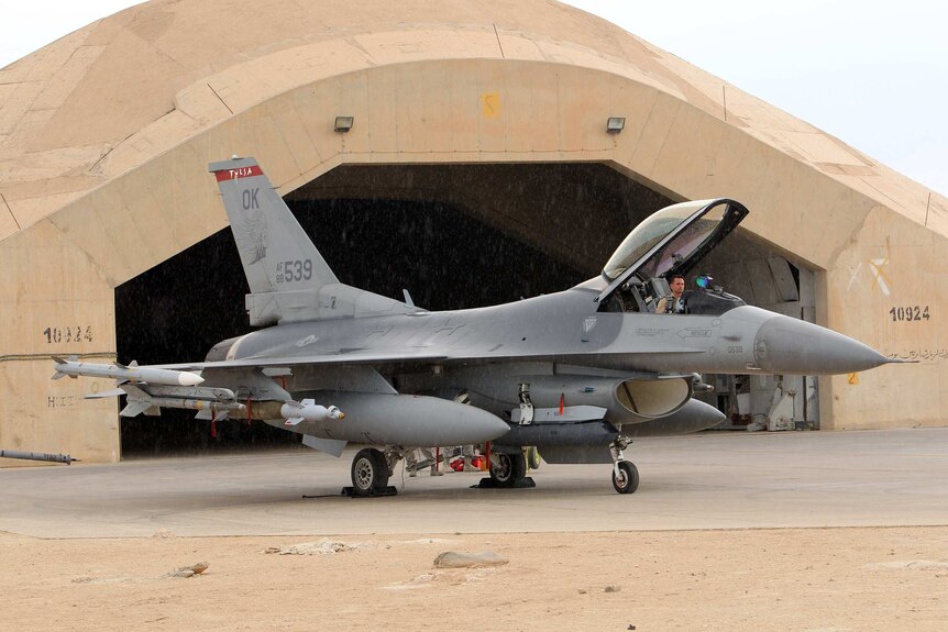 A pilot sits in a US F16 jet fighter at the Al Asad Air Base