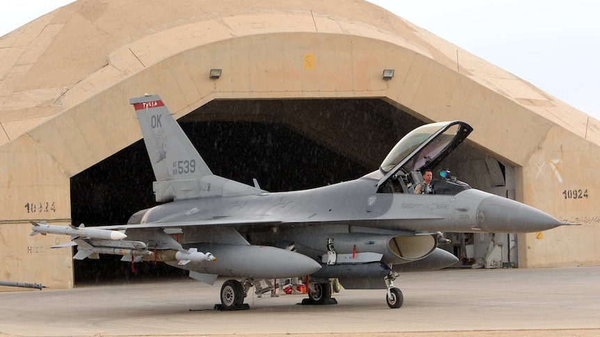 A pilot sits in a US F16 jet fighter at the Al Asad Air Base