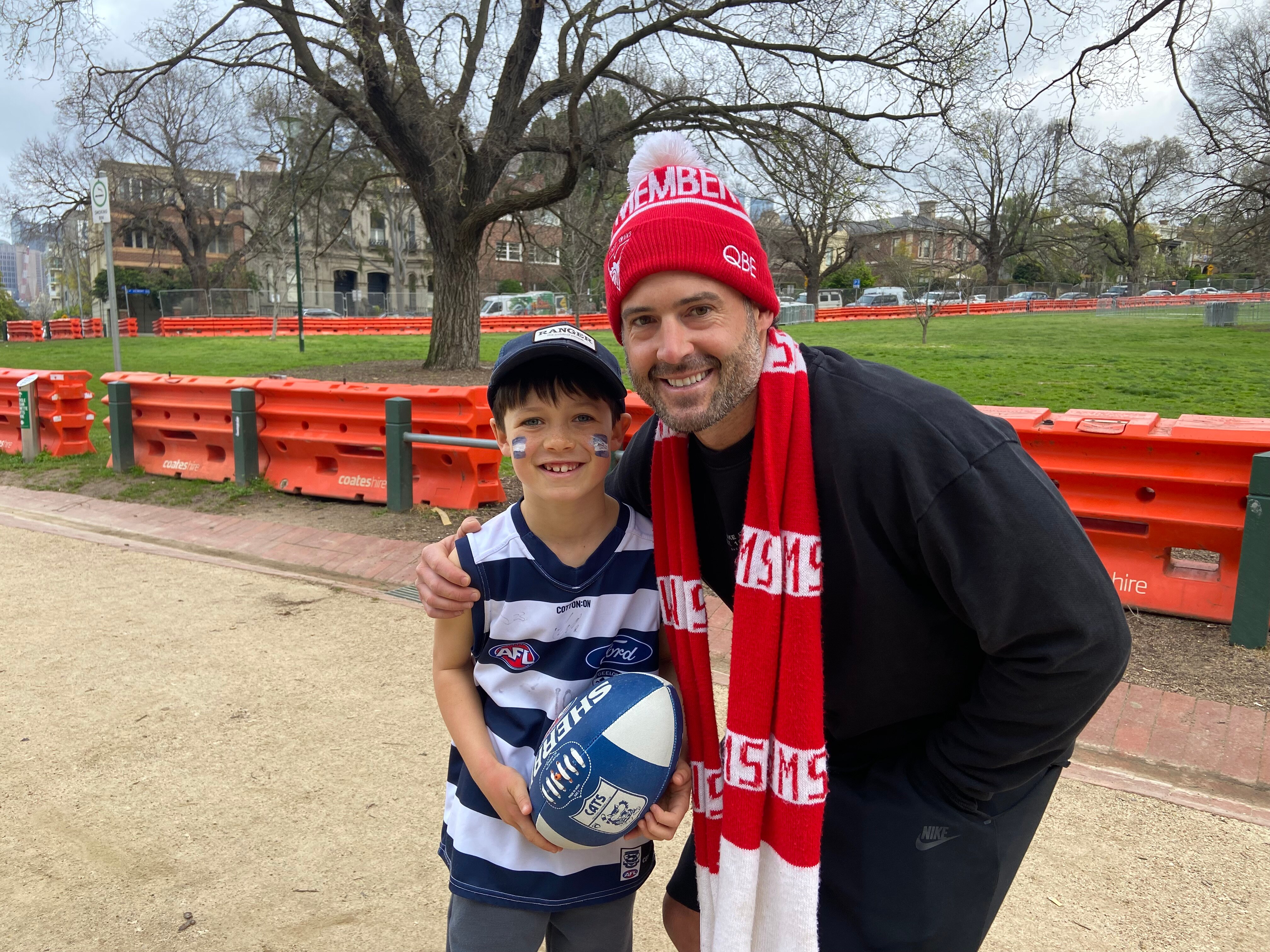 A boy and a man wearing football memorabilia.