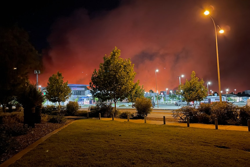 Red smoke plumes behind a suburban car park. 
