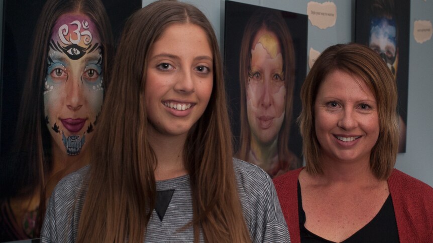 Daughter and mother caring team Jade and Danielle stand near their portraits.