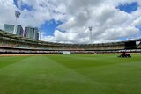 A view across the ground at the Gabba with light towers visible and a buildup of clouds overhead.