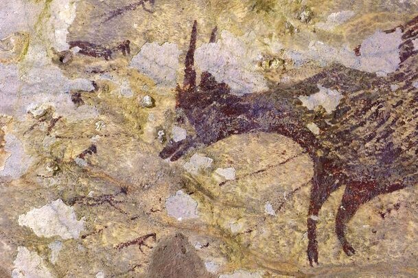 A cave painting portraying an animal and humans.
