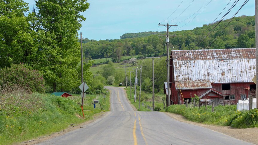 A red barn, a road, and rolling green hills