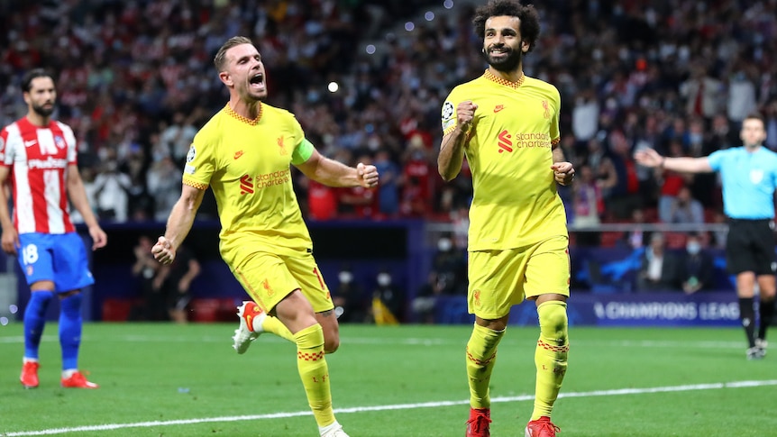 Mohamed Salah smiles and clenches his fist as Jordan Henderson screams in delight behind him