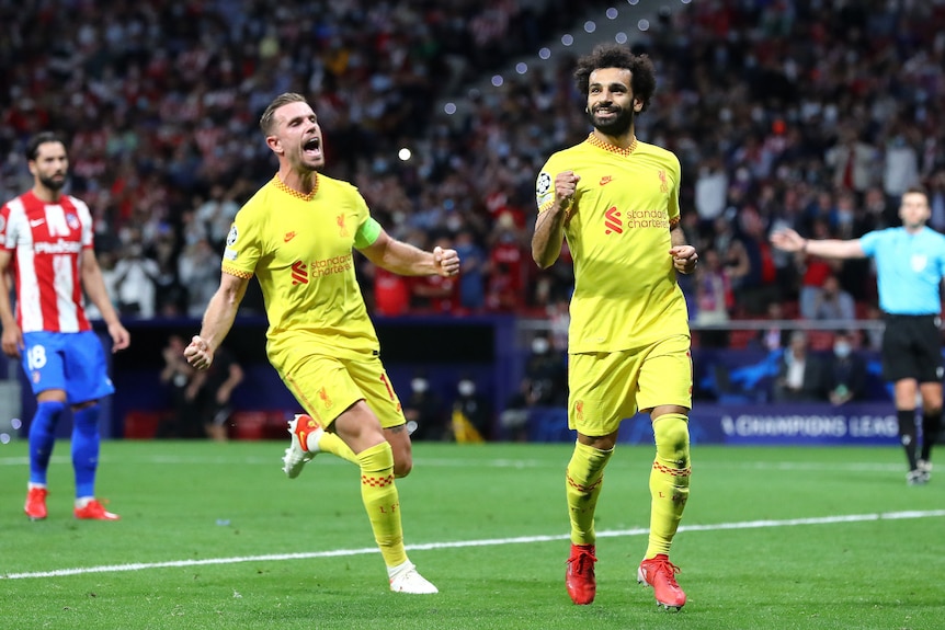 Mohamed Salah smiles and clenches his fist as Jordan Henderson screams in delight behind him