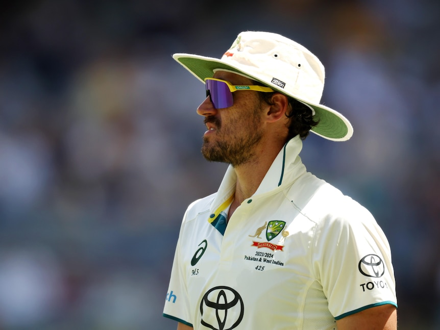 Mitchell Starc on the field wearing his whites and a floppy hat