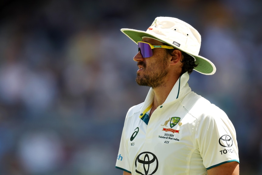 Mitchell Starc on the field wearing his whites and a floppy hat