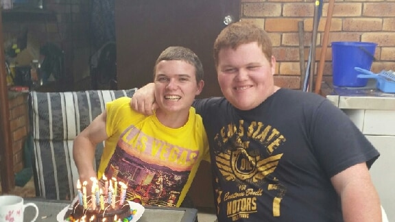 Josh Park-Fing with his twin brother sit arm in arm in front of two birthday cakes