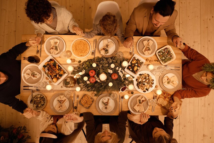 An aerial shot of a group of people sitting around a table to have a Christmas feast
