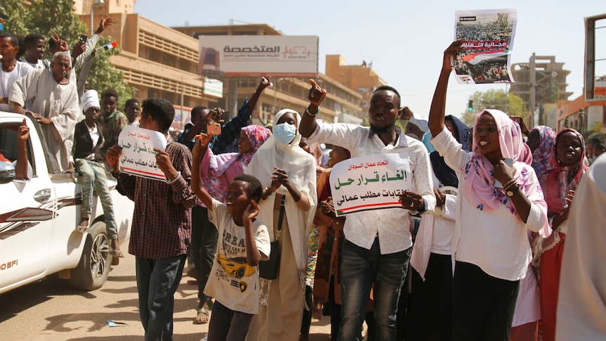 Sudanese protesters carry signs written in Arabic.