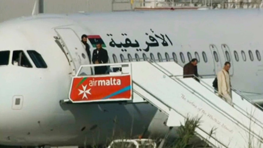 An Afriqiyah Airways plane stands on the tarmac at Malta International airport as passengers depart