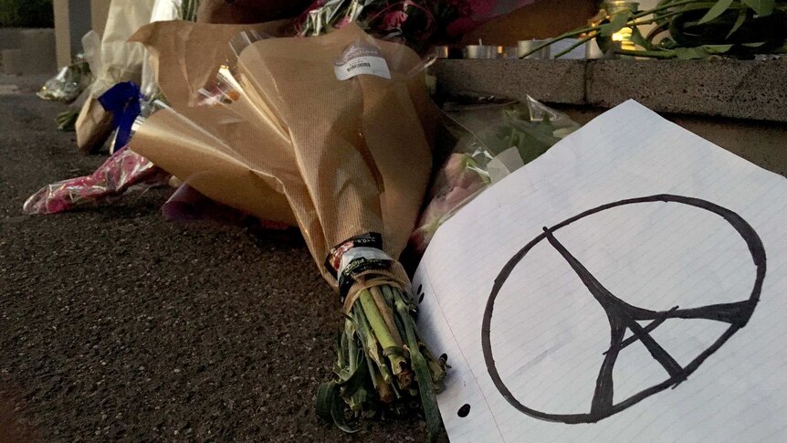 Flowers and a hand-drawn picture of the Paris peace sign outside the French consulate in Melbourne.
