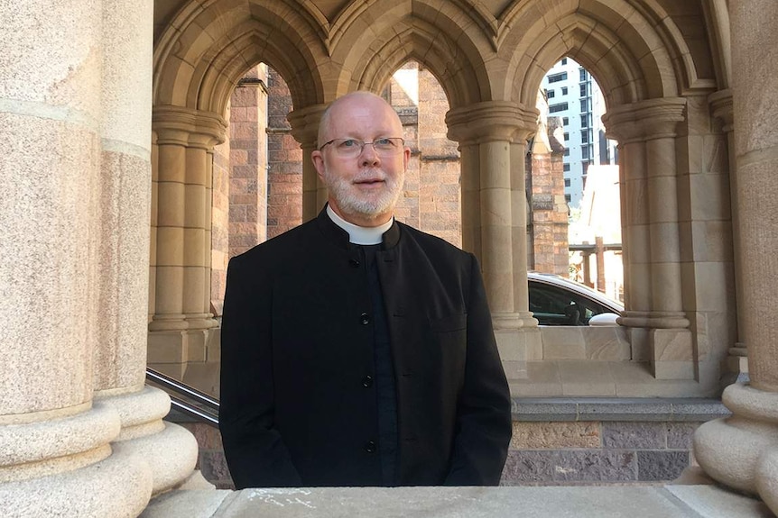 the Very Reverend Peter Catt and Anglican Dean of Brisbane stands in a church window